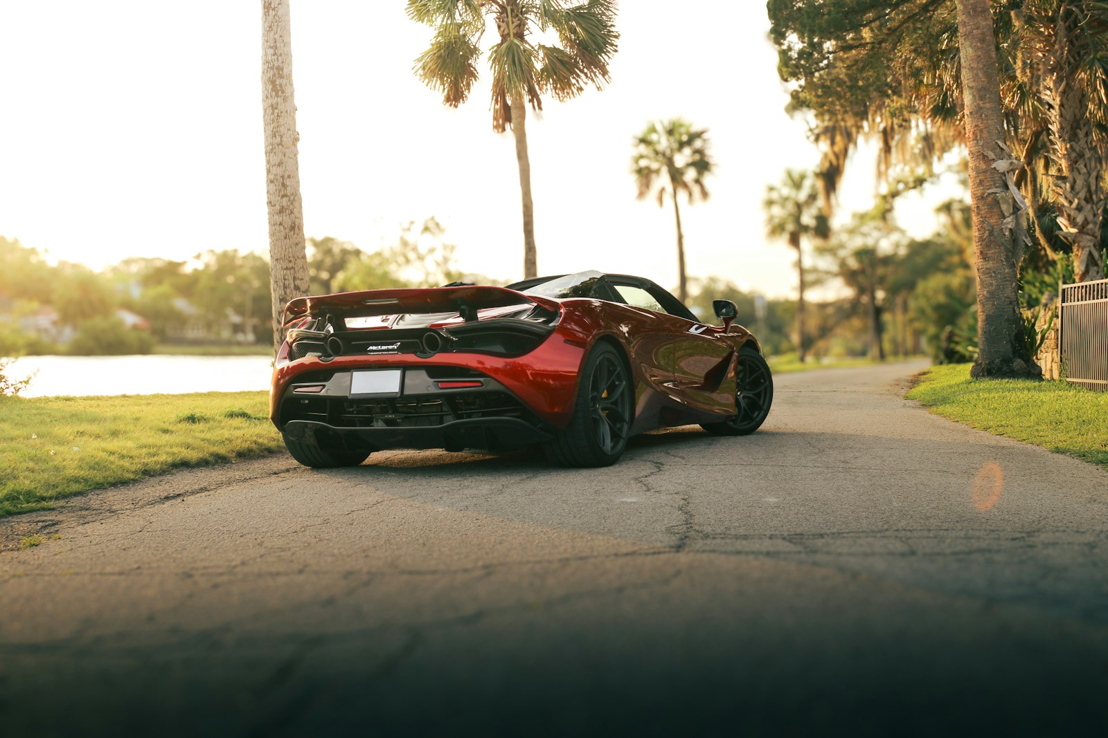 A red mclaren cruises down a scenic road.